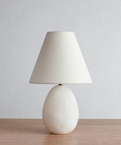 a white lamp sitting on top of a wooden table