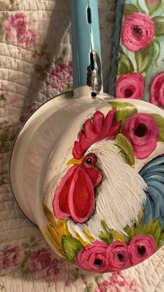 a rooster painted on the side of a toilet paper holder with pink flowers around it