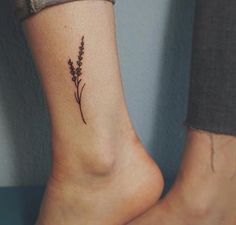 a woman's foot with a small flower tattoo on the side of her leg