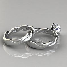 two wedding rings made out of silver with a diamond in the middle, on a reflective surface