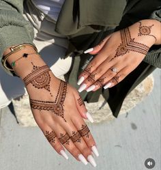 two women's hands with henna tattoos on them