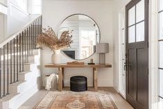 an entryway with a mirror, rug and vase on the floor in front of it