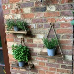 three hanging planters on a brick wall with potted plants attached to the shelves