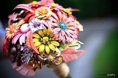 the brides bouquet is made up of colorful flowers and leaves, including daisies