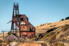 an old rusted building on the side of a hill