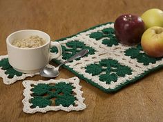 a bowl of oatmeal next to two apples on a table with crocheted placemats