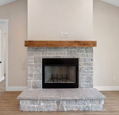 an empty living room with a stone fireplace