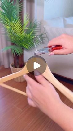 a woman is cutting wood with scissors on a table in front of a potted plant