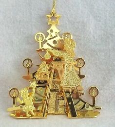 a gold christmas tree ornament hanging on a white background with stars and other decorations