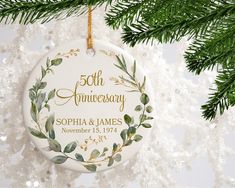 a 50th anniversary ornament hanging from a christmas tree with greenery on it