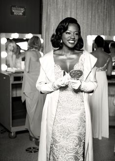 a woman standing in front of a mirror wearing a robe and holding a glass jar