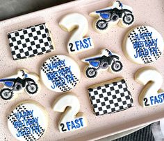 decorated cookies in the shape of motorbikes are on a pink tray with black and white checkers