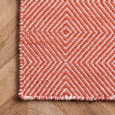 an orange and white rug on top of a wooden floor