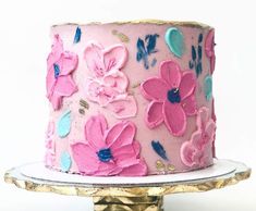 a pink and blue decorated cake sitting on top of a gold plated platter