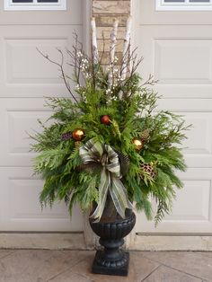 a vase filled with lots of greenery next to a door