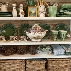 the shelves are filled with dishes, cups and other decorative items in wicker baskets