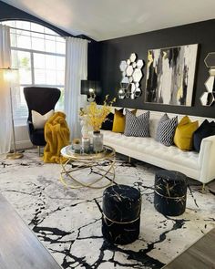 a living room with black and white furniture, yellow accents and art work on the wall