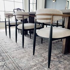 a dining room table with six chairs and a rug on the floor in front of it