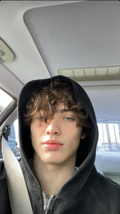 a young man with curly hair wearing a hoodie