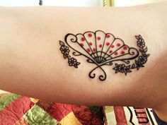 a woman's arm with a tattoo on it that has an image of a fan