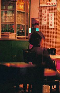 two people sitting at a table in front of a bar with neon signs on the wall