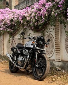 a motorcycle parked in front of a wall with flowers growing on it's sides