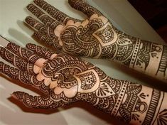 two hands with henna designs on them, one is showing off the intricate design