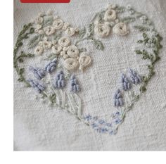 a close up of a heart shaped embroidered on a piece of cloth with flowers in the middle