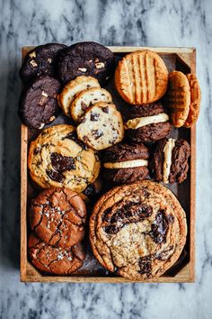 a wooden box filled with assorted cookies and cookies on top of a marble counter