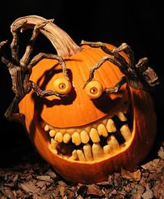 a carved pumpkin with eyes and teeth on it's face, sitting in leaves