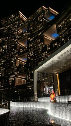 the building is lit up at night and has fountains running down it's sides