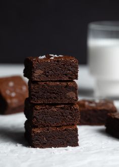 chocolate brownies stacked on top of each other next to a glass of milk