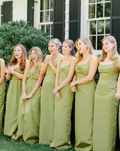 a group of women standing next to each other in long green dresses and smiling at the camera