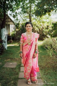 a woman in a pink and gold sari poses for the camera with her hand on her hip