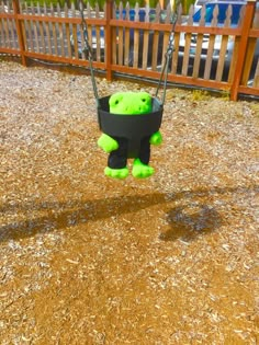 a green teddy bear sitting in a swing