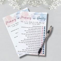 two baby shower game cards next to a pen on a table with flowers in the background