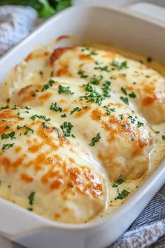 a casserole dish with cheese and parsley in it on a tablecloth