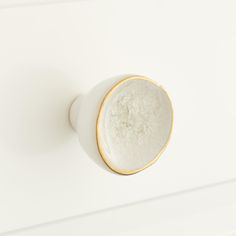 a close up of a white door knob with gold trim on a white cabinet top