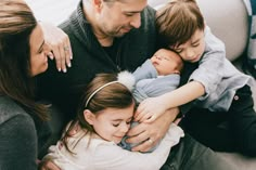 a group of people sitting on top of a couch with a baby in their arms