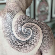 a man's back with an intricate tattoo design on his upper arm and shoulder