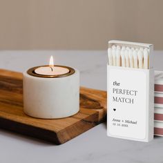 a match box next to a candle on a wooden tray