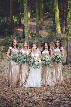 a group of women standing next to each other holding bouquets in front of trees