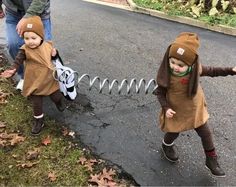 two young children dressed in costumes playing on the street