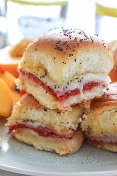 three sandwiches stacked on top of each other with fruit in the backgroung