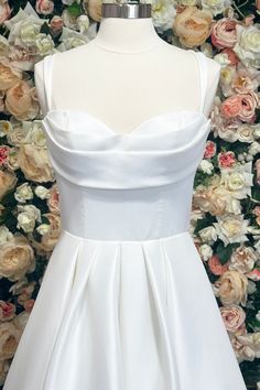 a white dress on a mannequin in front of flowers