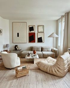 a living room filled with furniture and paintings on the wall above it's windows