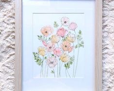 an image of flowers painted on paper in a white frame with some green leaves around it