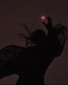 the silhouette of a woman with her hair blowing in the wind, against a dark background