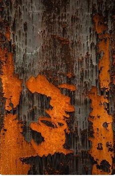 an old rusted metal surface with orange and black paint peeling off the edges,