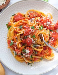 a plate of spaghetti with tomato sauce and parmesan cheese on top, ready to be eaten